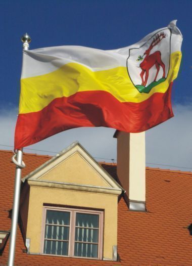 Flaga Jeleniej Góry powiewająca na wietrze przed budynkiem Urzędu Miasta